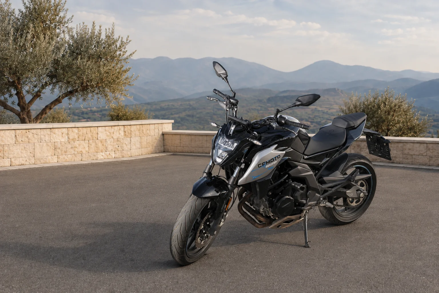 Siyah ve gri CFMOTO motosiklet, taş teras ve dağ manzarası önünde